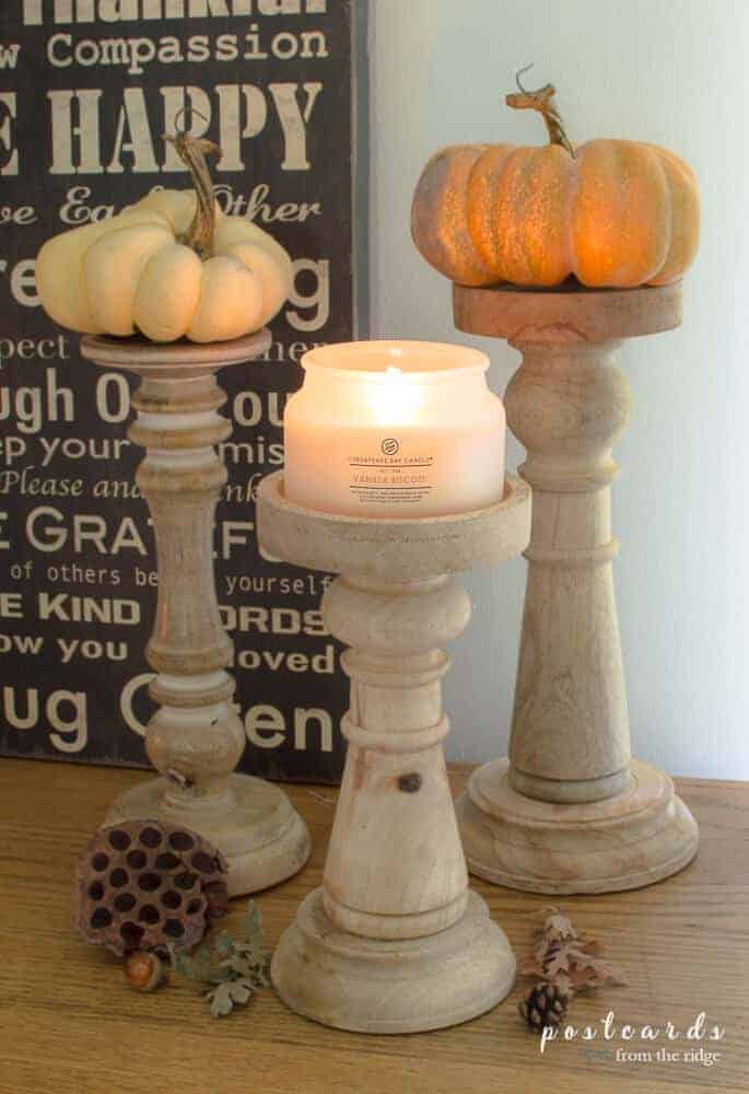 realistic faux pumpkins on wooden candlesticks