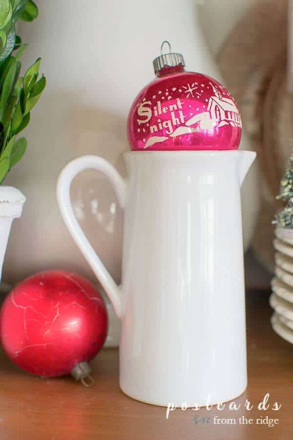 vintage pink shiny brite ornament sitting on top of ironstone creamer