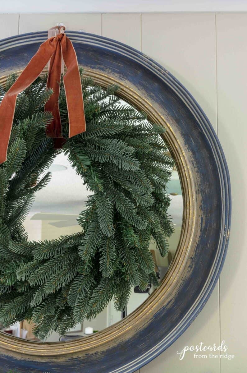 king of Christmas fir artificial wreath with velvet ribbon on a round mirror