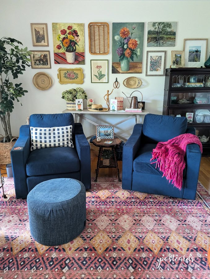 Lovesac Snugg chairs in dark blue velvet fabric with blue squattoman and wall full of art
