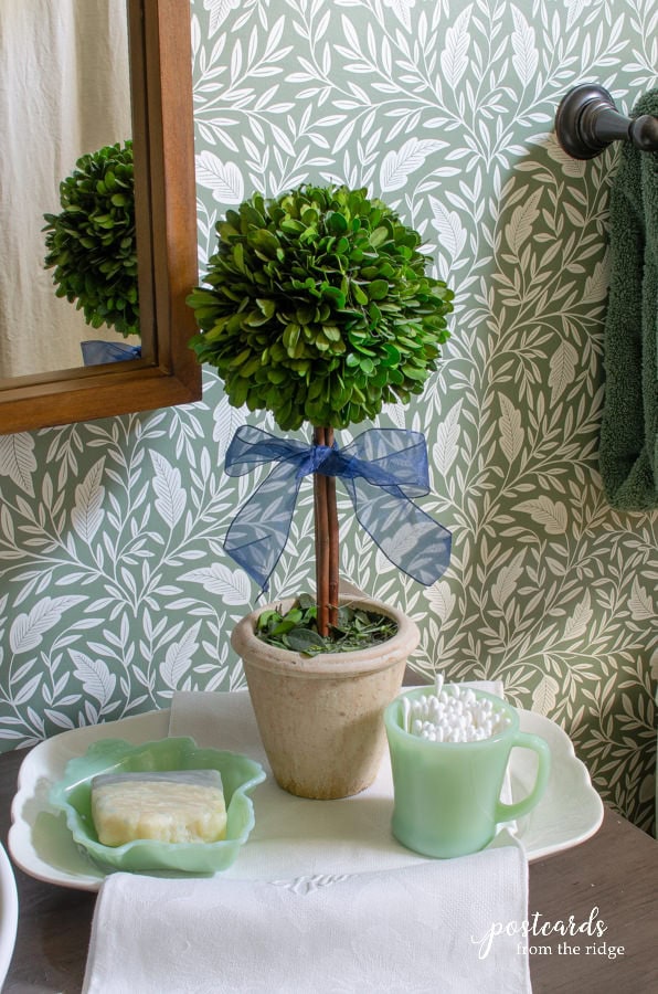 boxwood topiary and vintage jadeite with soap and q tips on top of a bathroom vanity