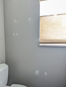 wall with nail holes patched with spackling compound before hanging wallpaper