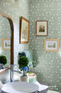 bathroom with green and white wallpaper and vintage wall art