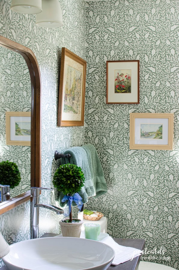 bathroom with green and white wallpaper and vintage wall art